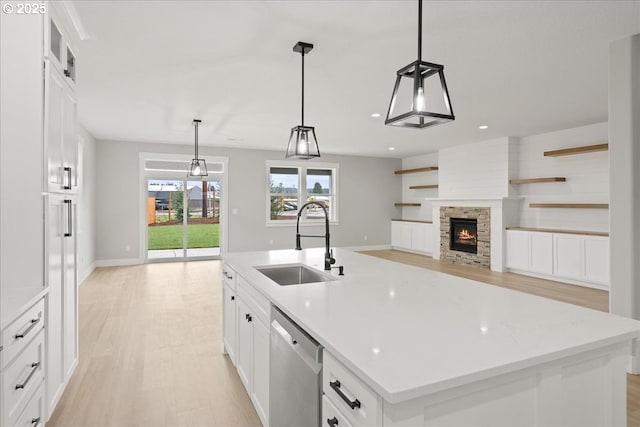 kitchen with white cabinets, dishwasher, a fireplace, open shelves, and a sink