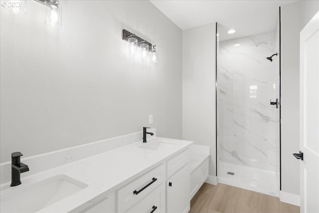 bathroom with a sink, a marble finish shower, and double vanity