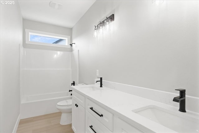 bathroom featuring toilet, tub / shower combination, a sink, and wood finished floors