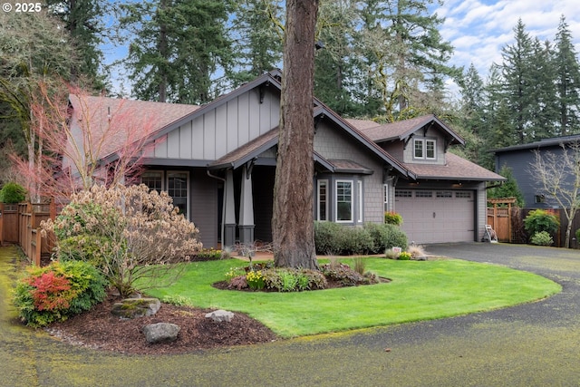 craftsman inspired home featuring board and batten siding, aphalt driveway, fence, and a front yard