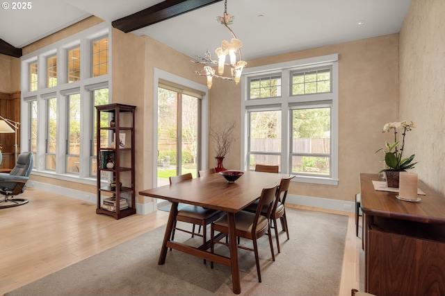 dining room featuring beamed ceiling, baseboards, a chandelier, and light wood finished floors