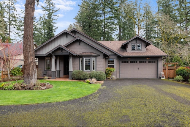 craftsman inspired home featuring driveway, fence, a front yard, a shingled roof, and a garage