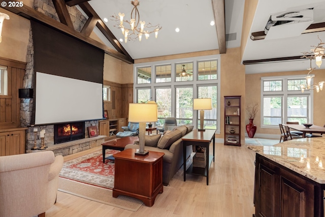 living area featuring beam ceiling, an inviting chandelier, a fireplace, and high vaulted ceiling