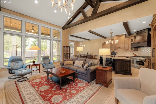 living area with beamed ceiling, a notable chandelier, and high vaulted ceiling