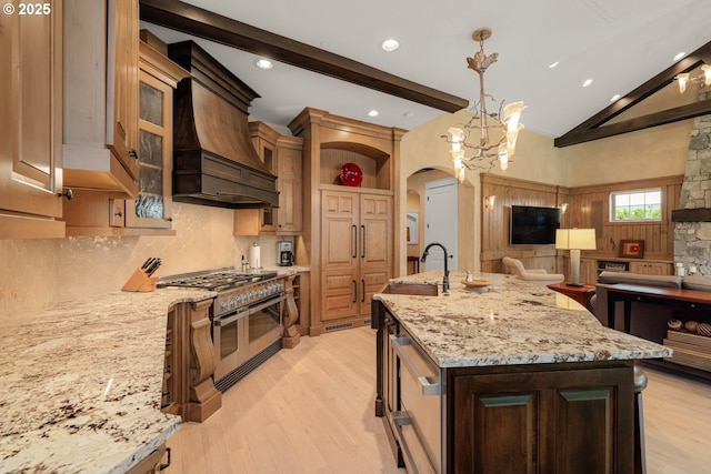 kitchen with open floor plan, custom range hood, range with two ovens, arched walkways, and a sink