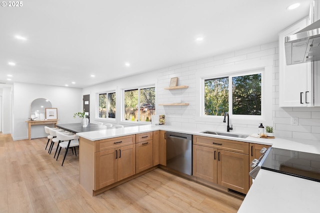 kitchen with dishwasher, sink, decorative backsplash, light wood-type flooring, and kitchen peninsula