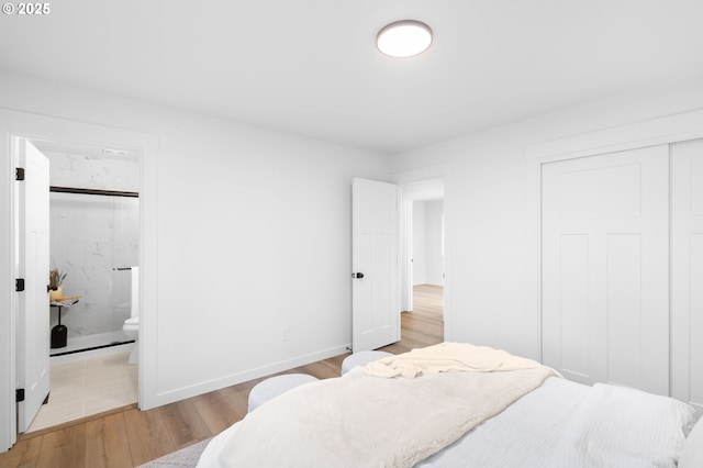 bedroom featuring connected bathroom and light wood-type flooring