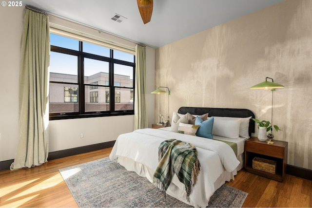 bedroom featuring wood finished floors, visible vents, and baseboards