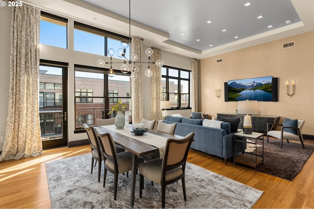 dining area featuring a chandelier, recessed lighting, wood finished floors, visible vents, and a tray ceiling