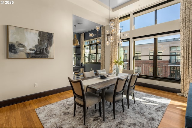 dining room with a high ceiling, baseboards, and wood finished floors