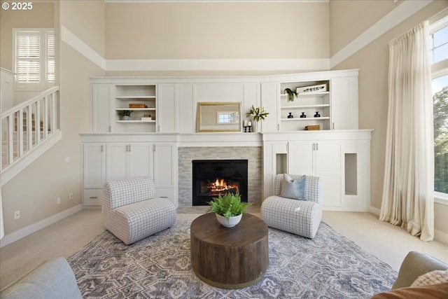 9037 NW Murdock St, Portland, OR 97229 - carpeted living room with a towering ceiling, a lit fireplace, baseboards, and stairs