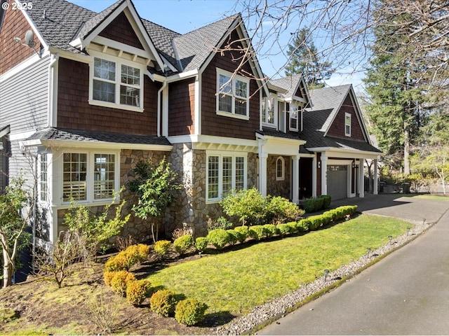 view of front facade with a front lawn, stone siding, and driveway