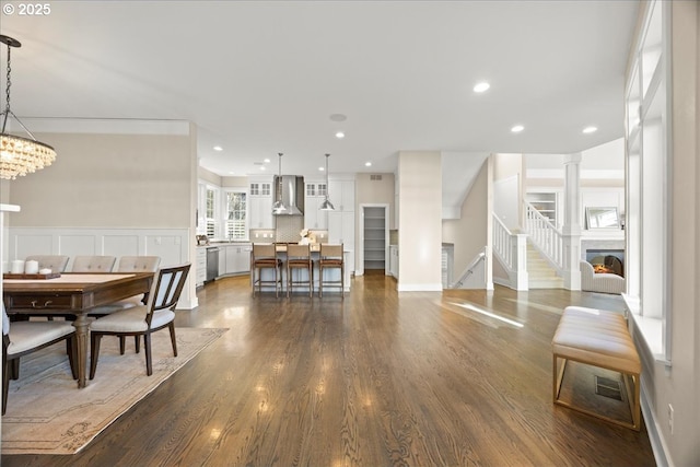 9037 NW Murdock St, Portland, OR 97229 - dining area featuring stairs, dark wood-style floors, recessed lighting, a lit fireplace, and baseboards