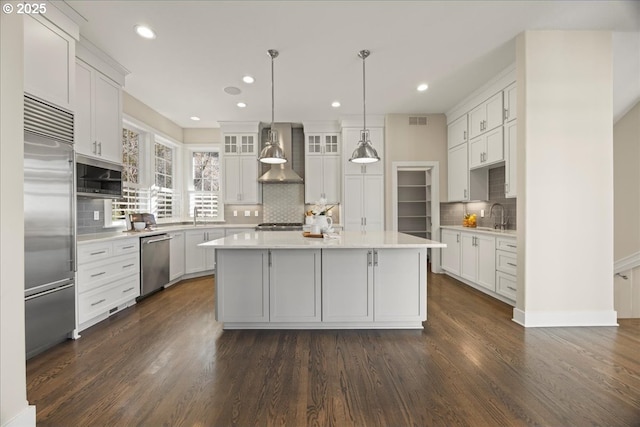 9037 NW Murdock St, Portland, OR 97229 - kitchen with appliances with stainless steel finishes, wall chimney exhaust hood, tasteful backsplash, light countertops, and dark wood finished floors