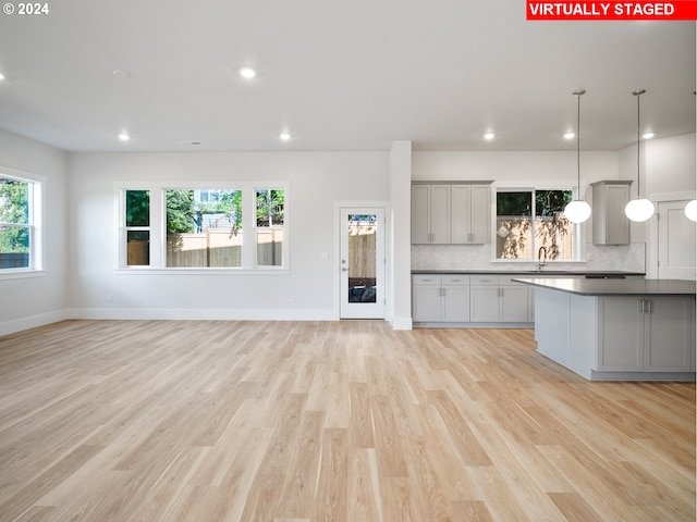 unfurnished living room with light wood-style floors, baseboards, a sink, and recessed lighting