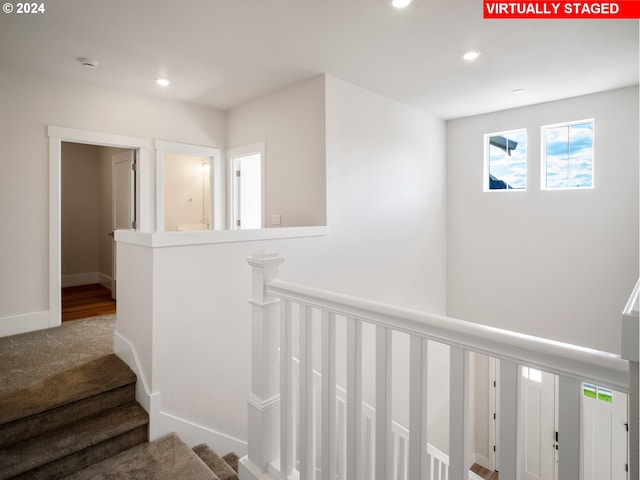 hall with carpet floors, an upstairs landing, baseboards, and recessed lighting