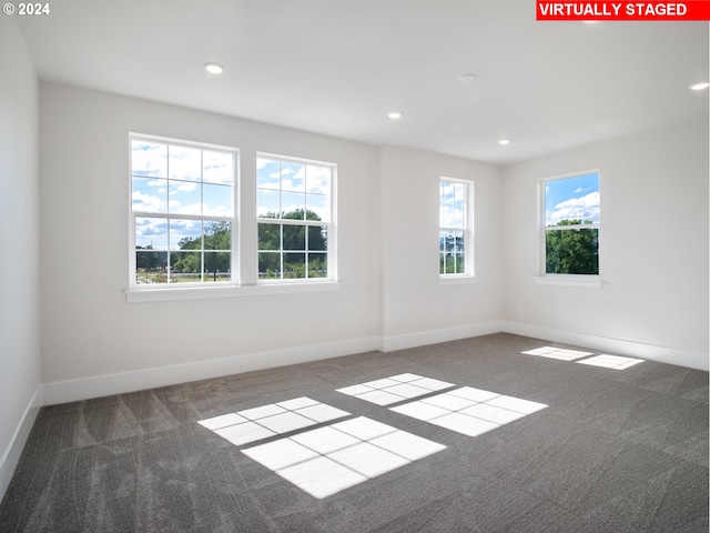 spare room featuring baseboards, dark carpet, and recessed lighting