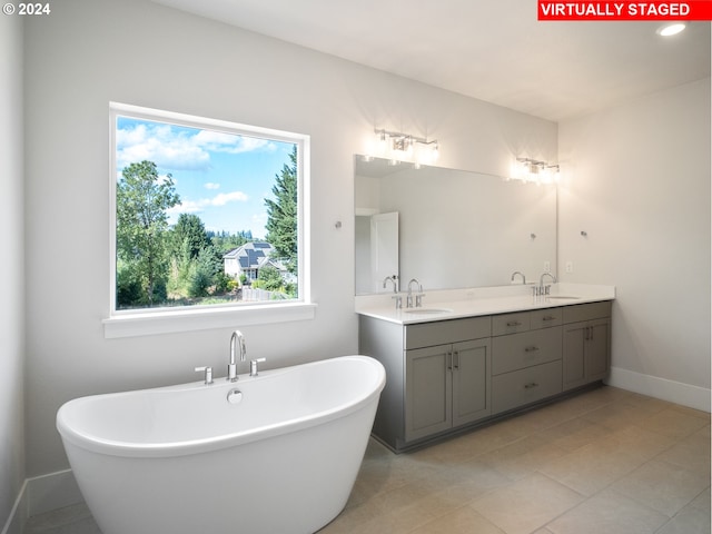 bathroom with double vanity, a freestanding tub, baseboards, and a sink