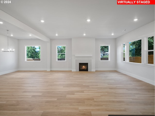 unfurnished living room featuring light wood-type flooring, recessed lighting, a warm lit fireplace, and baseboards