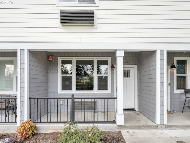 entrance to property featuring a porch and a wall mounted air conditioner