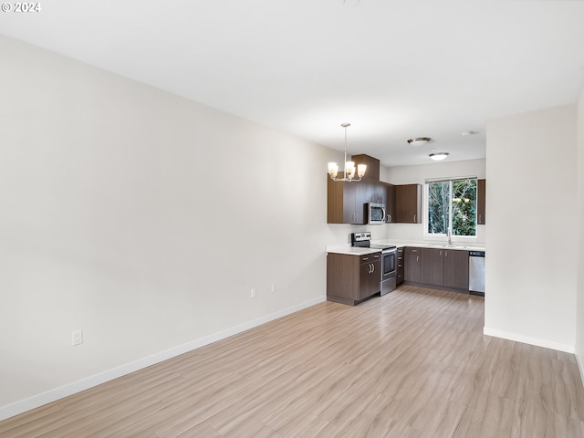 kitchen featuring sink, appliances with stainless steel finishes, dark brown cabinets, a chandelier, and light wood-type flooring