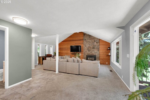 unfurnished living room featuring wood walls, lofted ceiling, and a healthy amount of sunlight