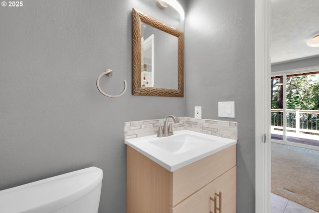 bathroom featuring decorative backsplash, toilet, vanity, and tile patterned flooring