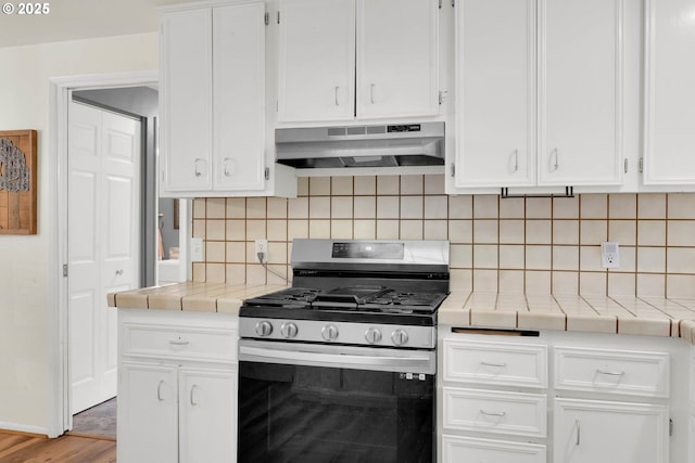 kitchen with white cabinets, gas stove, tile counters, and tasteful backsplash