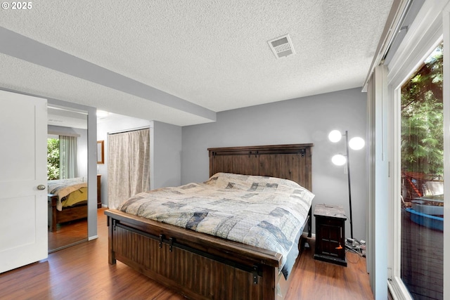 bedroom with a textured ceiling and dark hardwood / wood-style flooring