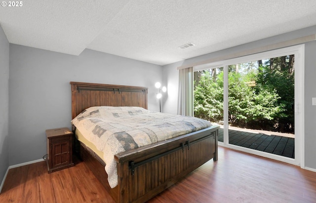 bedroom featuring wood-type flooring, a textured ceiling, and access to outside