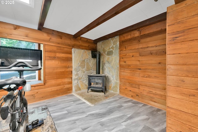 exercise room with a wood stove, a wealth of natural light, and wood walls