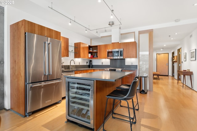 kitchen featuring sink, a center island, wine cooler, light hardwood / wood-style floors, and appliances with stainless steel finishes