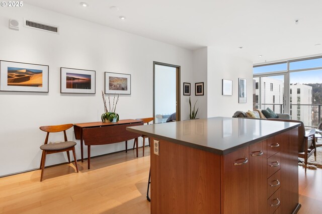 kitchen featuring a breakfast bar, a center island, light hardwood / wood-style flooring, and expansive windows