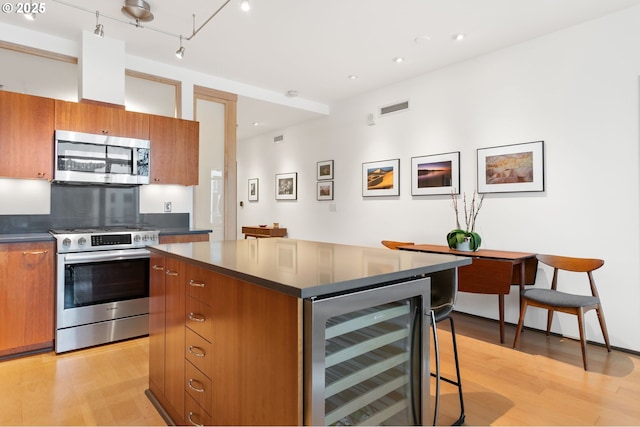 kitchen featuring track lighting, stainless steel appliances, a kitchen island, light hardwood / wood-style flooring, and wine cooler