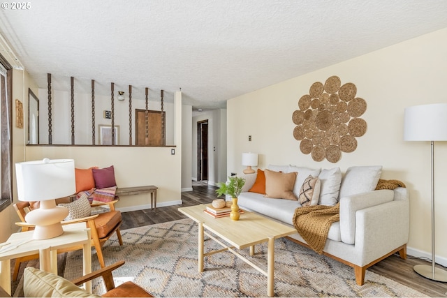 living room with a textured ceiling, baseboards, and wood finished floors