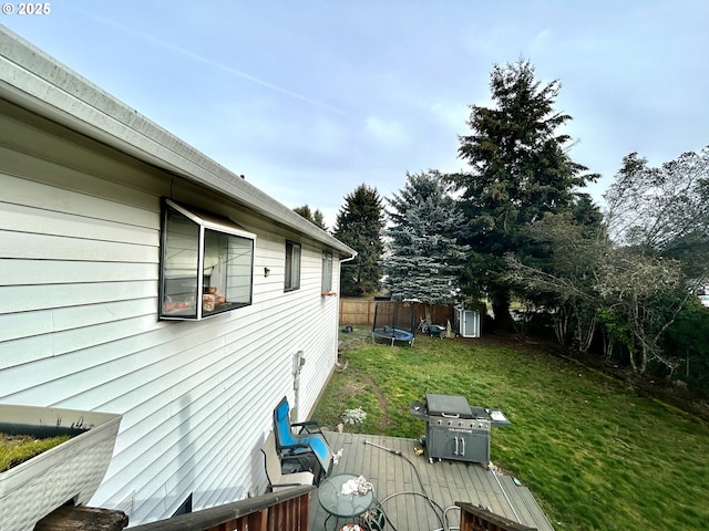 view of side of property featuring a trampoline and a lawn