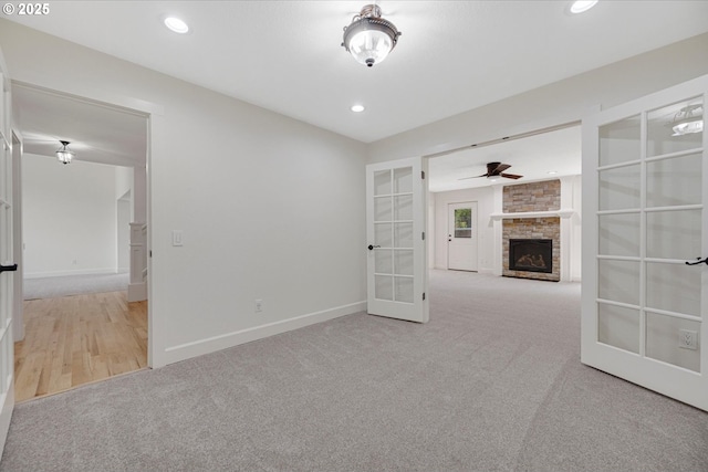 9240 SW Stono Dr, Tualatin, OR 97062 - carpeted spare room featuring french doors, a ceiling fan, a stone fireplace, and recessed lighting