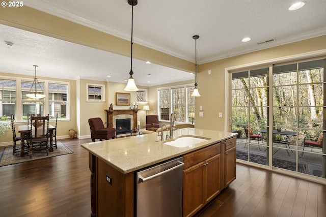 kitchen with a sink, crown molding, dark wood finished floors, a fireplace, and stainless steel dishwasher