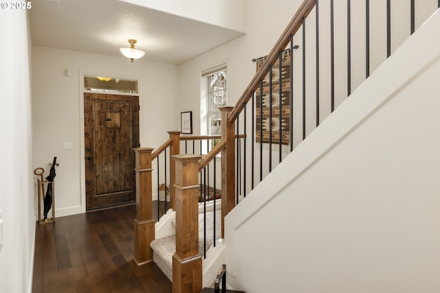 entrance foyer featuring stairs, baseboards, and dark wood-style flooring