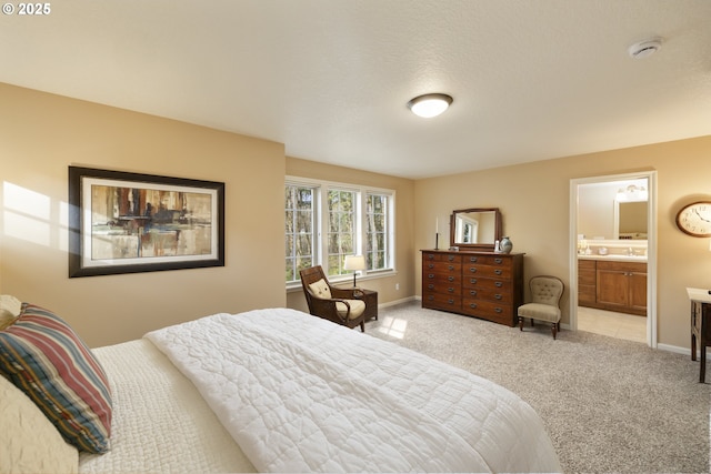 bedroom featuring a sink, connected bathroom, baseboards, and light carpet