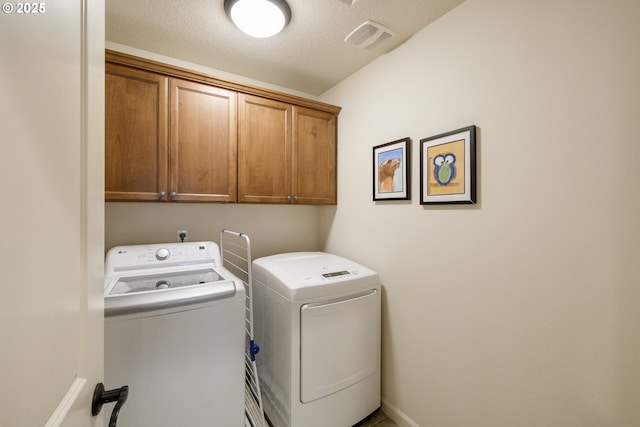 laundry room with visible vents, washer and dryer, a textured ceiling, cabinet space, and baseboards