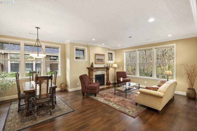 living room with dark wood finished floors, a textured ceiling, crown molding, and a tile fireplace