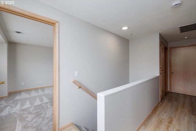 corridor with an upstairs landing, recessed lighting, wood finished floors, and baseboards