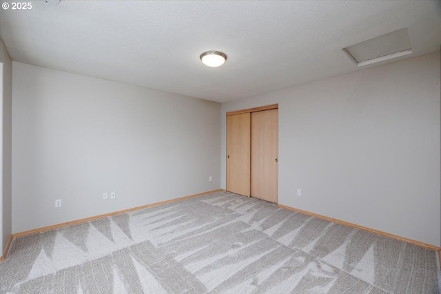 empty room with baseboards, light carpet, and attic access