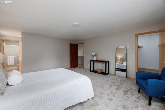 bedroom featuring light colored carpet, baseboards, and ensuite bath
