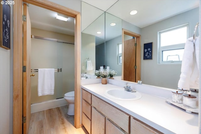 bathroom featuring wood finished floors, a shower stall, vanity, toilet, and recessed lighting