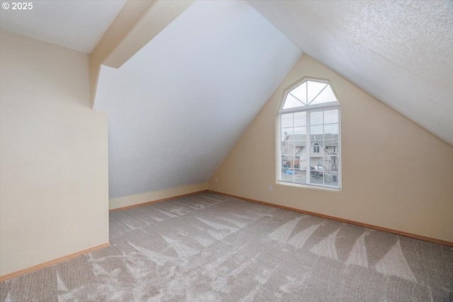 additional living space featuring carpet flooring, vaulted ceiling, and baseboards