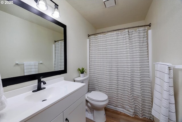 bathroom with wood finished floors, vanity, toilet, and a shower with curtain