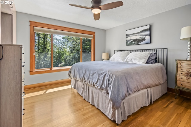 bedroom featuring wood finished floors, a ceiling fan, and baseboards