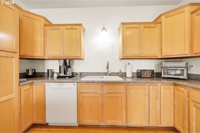 kitchen featuring light brown cabinetry, dishwasher, and sink